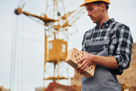Holds brick. Construction worker in uniform and safety equipment have job on buildingの写真素材