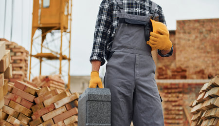 Hard hat and case in hands. Construction worker in uniform and safety equipment have job on building