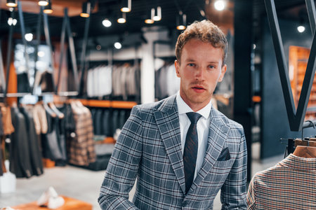 In jacket with tie. Young guy in modern store with new clothes. Elegant expensive wear for menの写真素材
