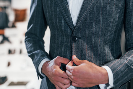 Close up view. Young guy in modern store with new clothes. Elegant expensive wear for menの写真素材