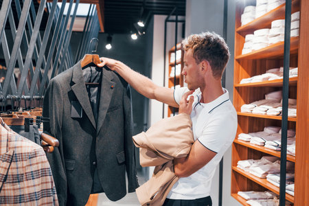 Looks for jacket. Young guy in modern store with new clothes. Elegant expensive wear for menの写真素材