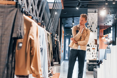 Quality products. Young guy in modern store with new clothes. Elegant expensive wear for menの写真素材