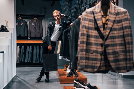 Weekend shopping. Young guy in modern store with new clothes. Elegant expensive wear for menの写真素材