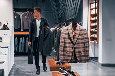 Choice has made. Young guy in modern store with new clothes. Elegant expensive wear for menの写真素材