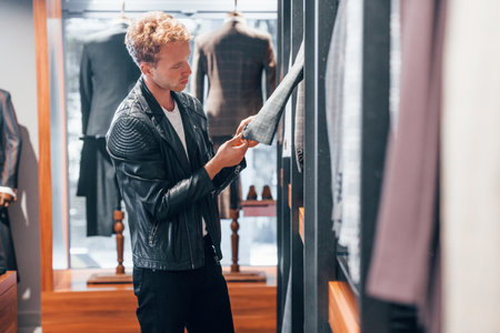 In beautiful black jacket. Young guy in modern store with new clothes. Elegant expensive wear for menの写真素材