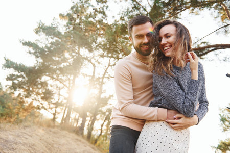 Embraces each other. Cheerful lovely young couple having a rest outdoors togetherの写真素材