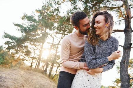 Embraces each other. Cheerful lovely young couple having a rest outdoors togetherの写真素材
