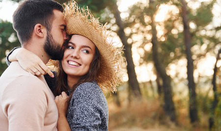 Standing and hugging. Cheerful lovely young couple having a rest outdoors togetherの写真素材