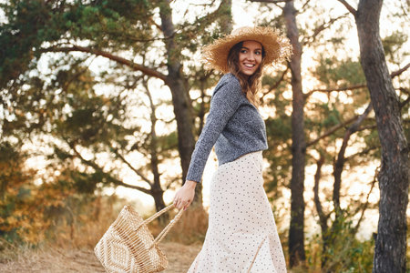 Happy young woman have a walk outdoors in the forest at sunny daytimeの写真素材