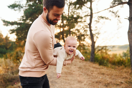 Bearded father playing with his child outdoors at sunny daytime outdoorsの写真素材