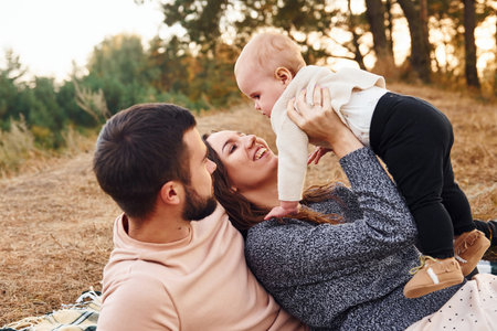 Haves picnic. Happy family of mother, family and little baby rests outdoors. Beautiful sunny autumn natureの写真素材