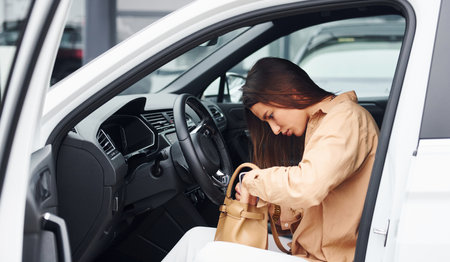 Serching something in bag. Fashionable beautiful young woman and her modern automobileの写真素材