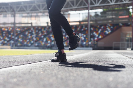 Close up view of legs of runner in black pants and shoes that is outdoors on the trackの写真素材