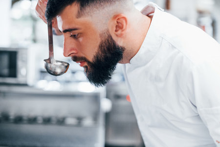 Cooks delicious soup. Chef in white uniform cooking food at kitchen. Busy day at workの写真素材