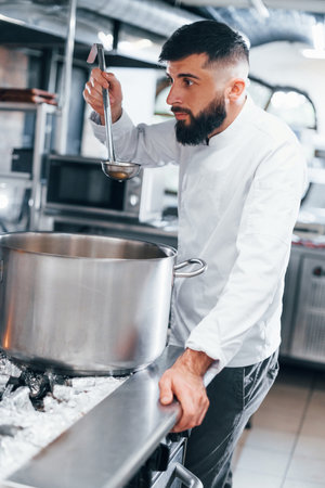 Cooks delicious soup. Chef in white uniform cooking food at kitchen. Busy day at workの写真素材
