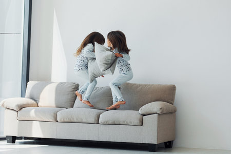 Pillow fight. Two cute little girls indoors at home together. Children having funの写真素材