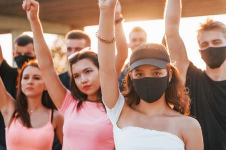 Fists rased high up. Group of protesting young people that standing together. Activist for human rights or against governmentの写真素材