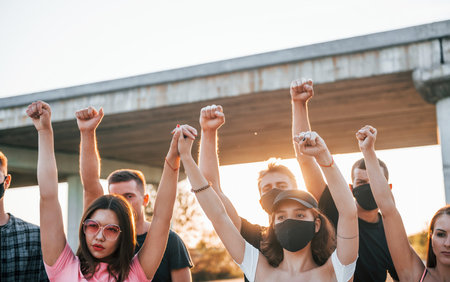 Fists rased high up. Group of protesting young people that standing together. Activist for human rights or against governmentの写真素材