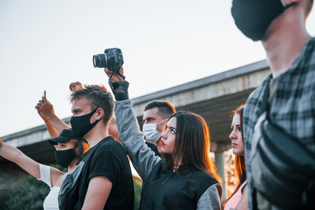 Photographer with camera. Group of protesting young people that standing together. Activist for human rights or against governmentの写真素材