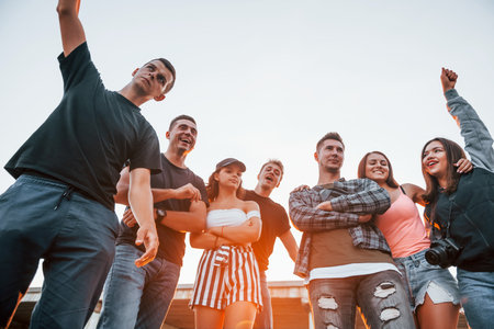 Posing for a camera. Group of young cheerful friends having fun together. Party outdoorsの写真素材