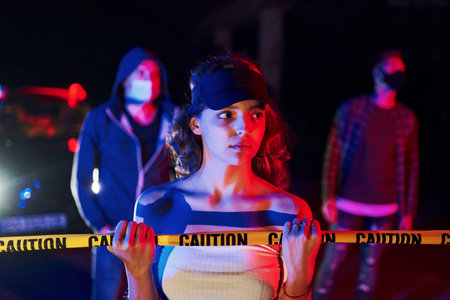 Girl leaning on police tape. Group of protesting young people that standing together. Activist for human rights or against governmentの写真素材