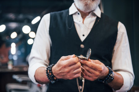 In retro clothes in barbershop. Stylish modern senior man with gray hair and beard is indoorsの写真素材