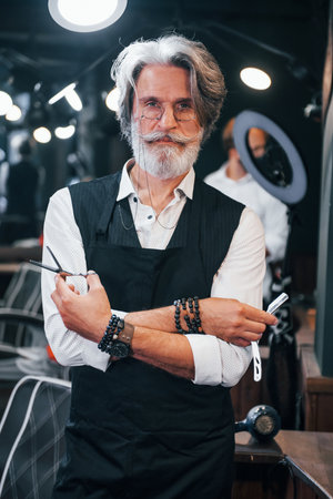 In barbershop. Stylish modern senior man with gray hair and beard is indoorsの写真素材