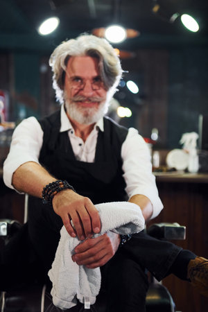In barbershop. Stylish modern senior man with gray hair and beard is indoorsの写真素材