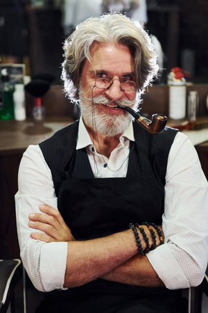 In barbershop. Stylish modern senior man with gray hair and beard is indoorsの写真素材