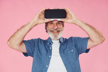 Virtual reality experience. Stylish modern senior man with gray hair and beard is indoorsの写真素材