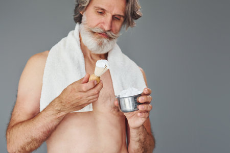 With shaving gel. Stylish modern senior man with gray hair and beard is indoorsの写真素材