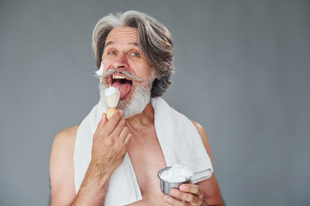 With shaving gel. Stylish modern senior man with gray hair and beard is indoorsの写真素材
