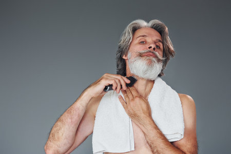 Taking care of beard. Stylish modern senior man with gray hair is indoorsの写真素材