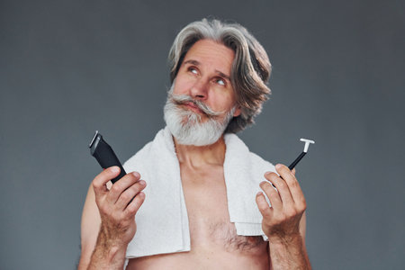 Taking care of beard. Stylish modern senior man with gray hair is indoorsの写真素材