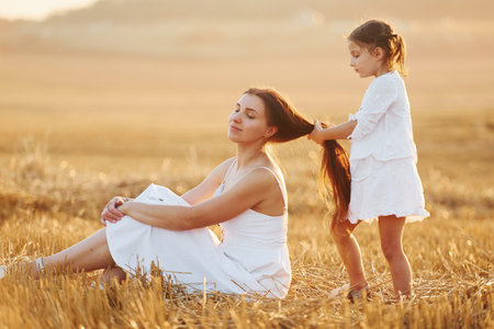 Happy mother with her little daughter spending time together outdoors on the fieldの写真素材