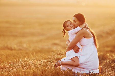 Positive little girl with her mother have weekend outdoors on the summer field togetherの写真素材