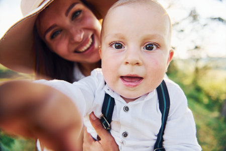 Young mother with her little son is outdoors in the forest. Beautiful sunshineの写真素材