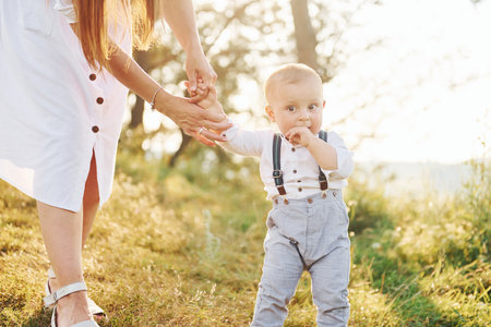 Young mother with her little son is outdoors in the forest. Beautiful sunshineの写真素材