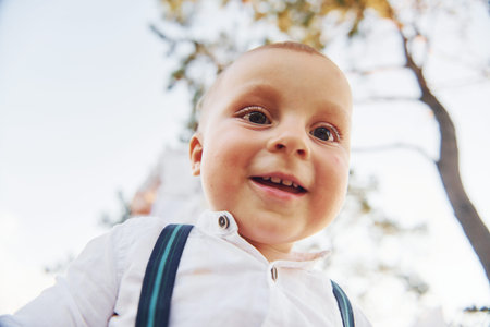 Portrait of happy little boy that standing and smiles to the camera outdoors