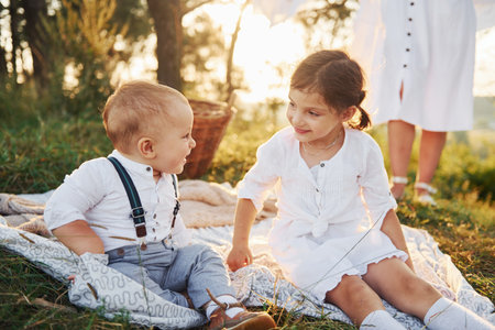 Young mother with her little daughter and son is outdoors in the forest. Beautiful sunshineの写真素材