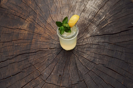 With lemon and mint. Close up view of fresh summer alcoholic cocktail on the wooden table