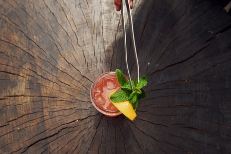 Waiters hand. With lemon and mint. Close up view of fresh summer alcoholic cocktail on the wooden tableの写真素材