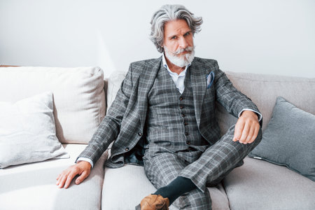 In apartment with elegant clothes. Senior stylish modern man with grey hair and beard indoorsの写真素材