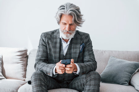 In apartment with elegant clothes. Senior stylish modern man with grey hair and beard indoorsの写真素材