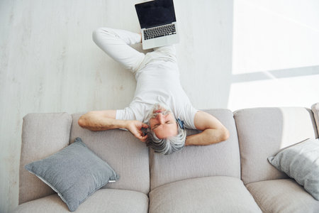 Enjoys music. Senior stylish modern man with grey hair and beard indoorsの写真素材
