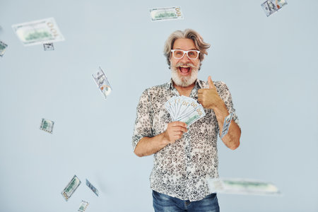 Millionaire with cash in hands. Senior stylish modern man with grey hair and beard indoorsの写真素材