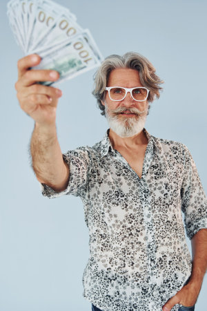 Millionaire with cash in hands. Senior stylish modern man with grey hair and beard indoorsの写真素材