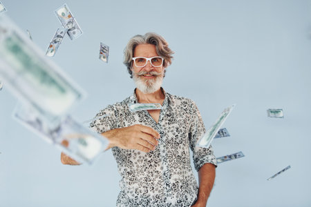 Millionaire with cash in hands. Senior stylish modern man with grey hair and beard indoorsの写真素材