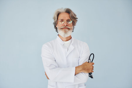 Doctor in white coat against wall. Senior stylish modern man with grey hair and beard indoorsの写真素材