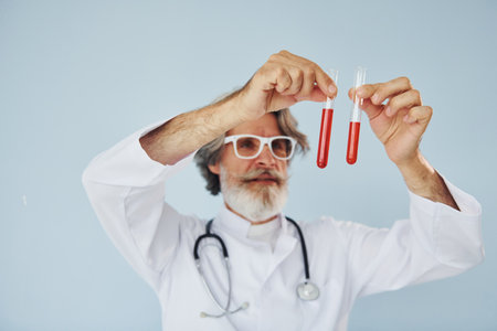 Doctor holds test tubes. Senior stylish modern man with grey hair and beard indoorsの写真素材